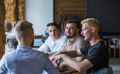 young-man-sitting-restaurant-explaining-strategy-his-friends